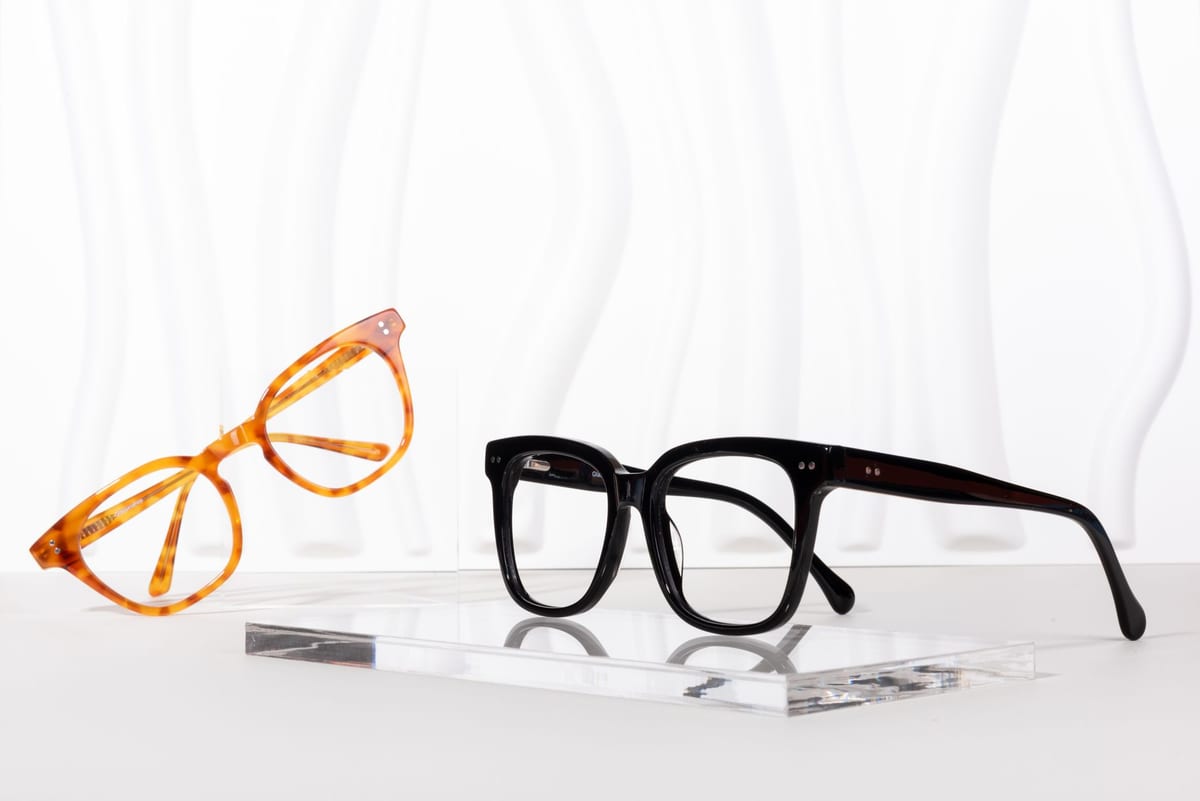 Two pairs of spectacle frames on a display riser