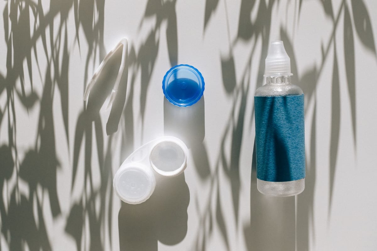 A contact lens case and solution bottle on a bright surface